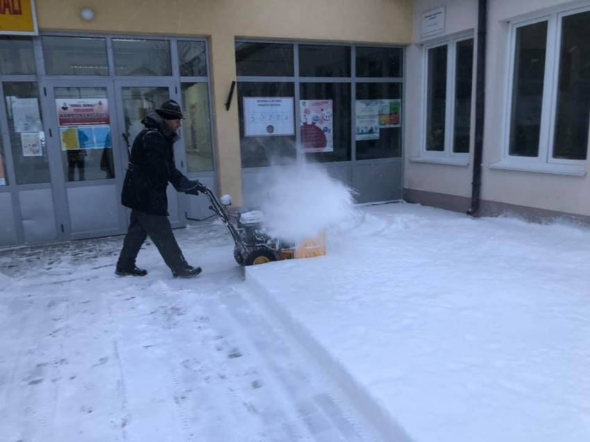 Mërgimtari heq borën nga oborri i qendrës së votimit..